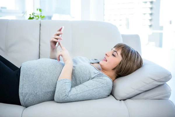 Schwangere nutzt Smartphone zu Hause — Stockfoto