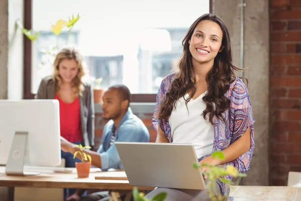 Zakenvrouw met behulp van laptop op creatieve kantoor — Stockfoto