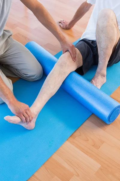 Treinador trabalhando com o homem no tapete de exercício — Fotografia de Stock