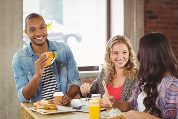 Man met hamburger met collega 's — Stockfoto