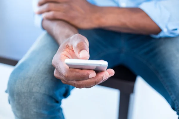 Uomo che utilizza il telefono cellulare mentre seduto — Foto Stock