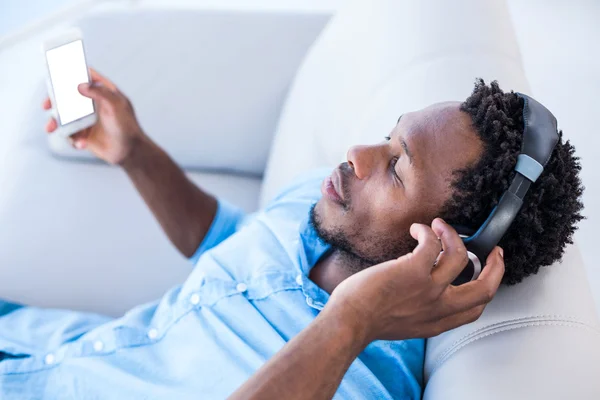 Человек наслаждается музыкой, расслабляясь на диване — стоковое фото