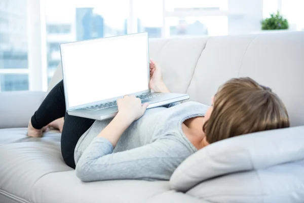 여자는 소파에 누워 있는 동안 노트북을 사용 하 여 — 스톡 사진