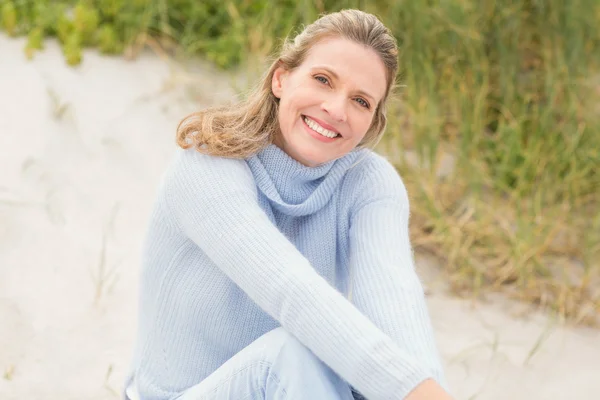 Lachende vrouw die zit op het zand — Stockfoto