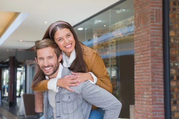 Man giving young woman piggy ride — Stock Photo, Image