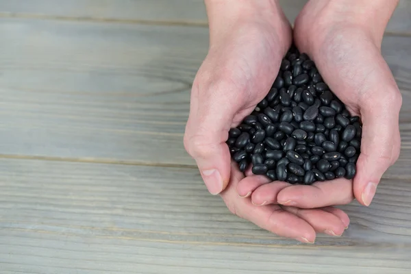 Frau zeigt Handvoll schwarze Bohnen — Stockfoto