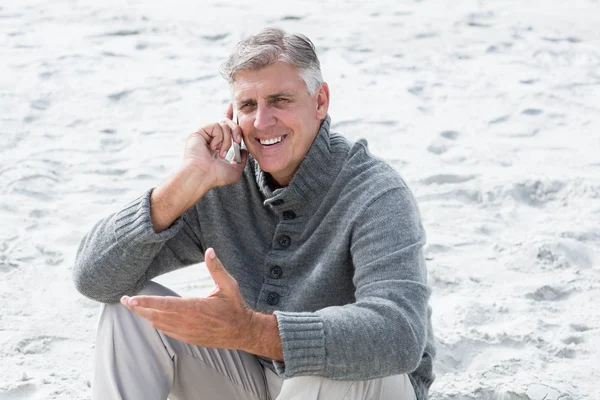 Uomo seduto con telefono in spiaggia — Foto Stock