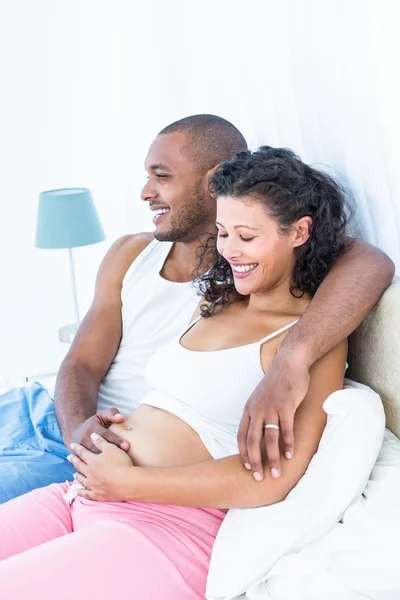Муж сидит на кровати с беременной женой — стоковое фото