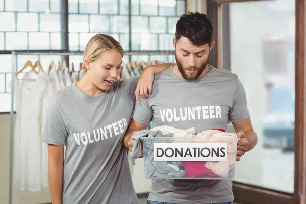 Volunteers looking at clothes in box — Stock Photo, Image