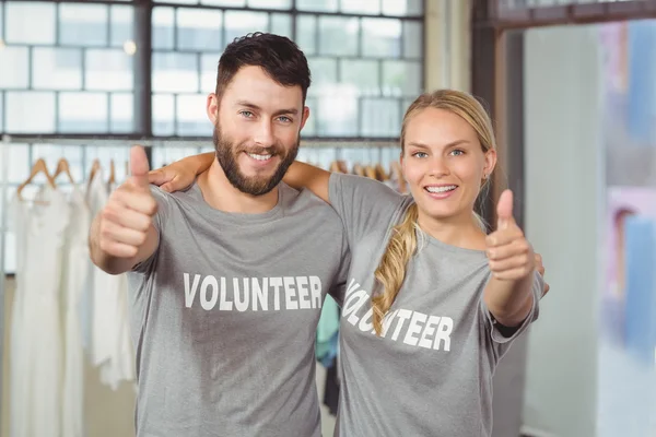 Smiling volunteers giving thumbs up — Stock Photo, Image