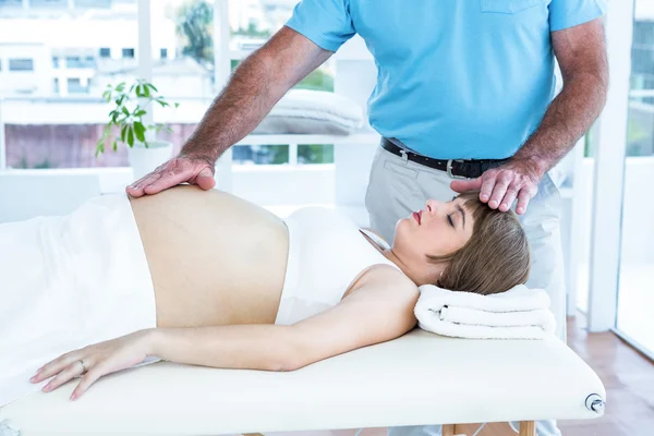 Pregnant woman getting reiki from male therapist — Stock Photo, Image