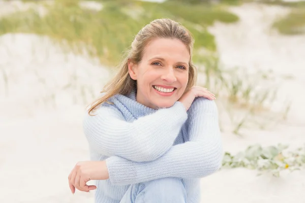 Lachende vrouw die zit op zand — Stockfoto