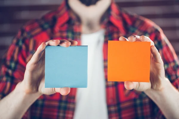 Hombre mostrando notas adhesivas anaranjadas y azules — Foto de Stock