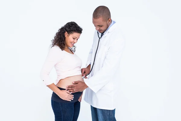 Médico sorridente examinando mulher grávida — Fotografia de Stock