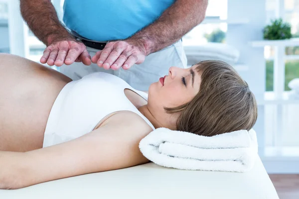 Terapeuta realizando reiki sobre la mujer embarazada —  Fotos de Stock