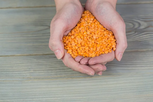 Woman showing handful of red lentils — Stock Photo, Image