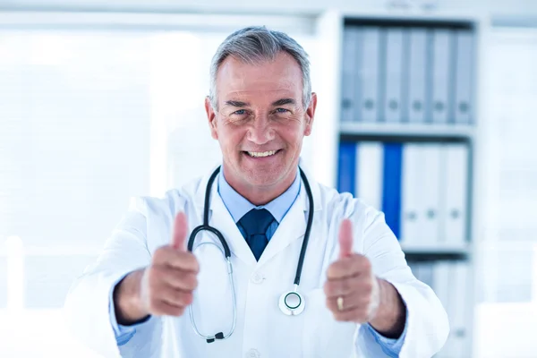 Doctor showing thumps up sign in clinic Stock Picture