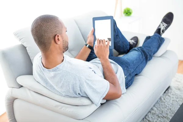 Mannen liggande på soffan använder tablet — Stockfoto