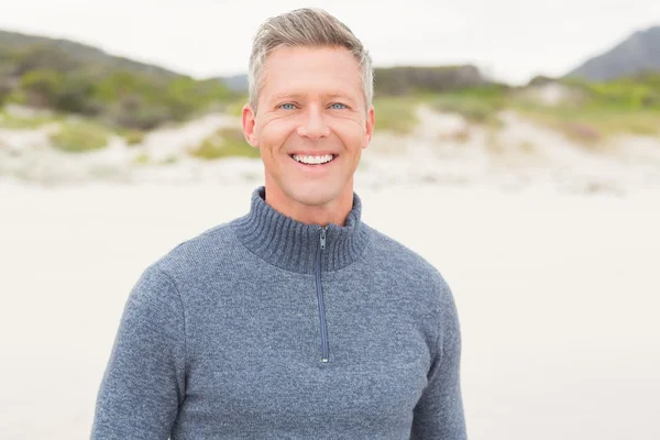 Uomo sorridente in piedi sulla spiaggia — Foto Stock