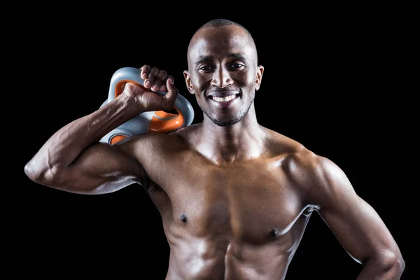 Homem sorrindo enquanto segurando kettlebell — Fotografia de Stock