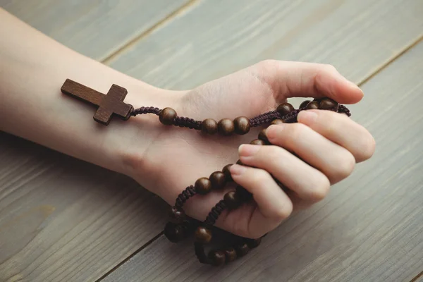 Woman holding wooden rosary beads — Stock Photo, Image