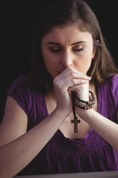 Mujer rezando con cuentas de rosario de madera — Foto de Stock