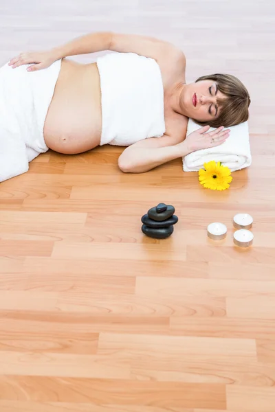 Mujer embarazada descansando sobre suelo de madera — Foto de Stock