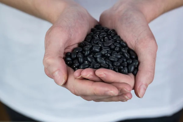 Mujer mostrando puñado de frijoles negros —  Fotos de Stock