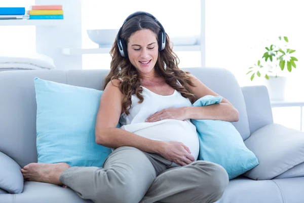 Femme enceinte écouter de la musique sur canapé — Photo