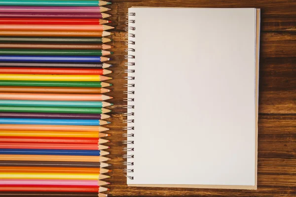 Lápis de cor na mesa com bloco de notas — Fotografia de Stock