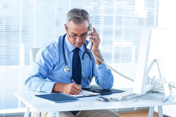 Läkare skriva dokument vita talar i telefon — Stockfoto