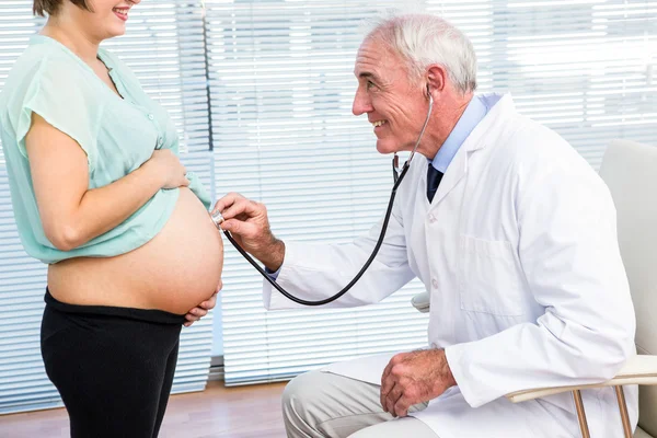 Médico examinando mulher grávida com estetoscópio — Fotografia de Stock