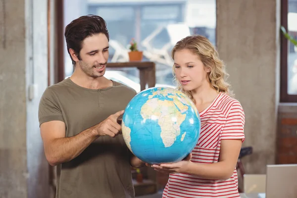 Colleagues looking at globe in office — Stock Photo, Image