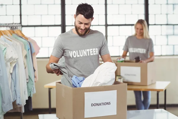 Hombre separando la ropa de la caja de donación — Foto de Stock