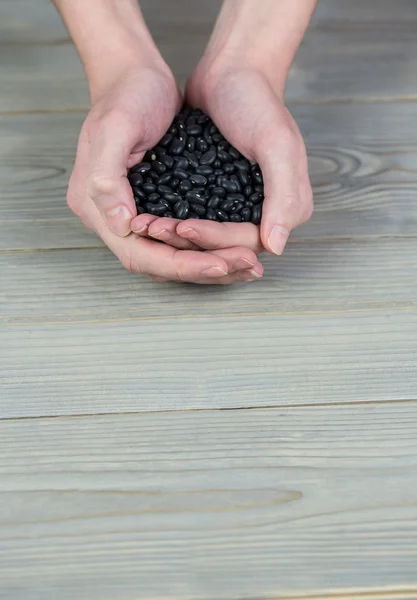 Frau zeigt Handvoll schwarze Bohnen — Stockfoto