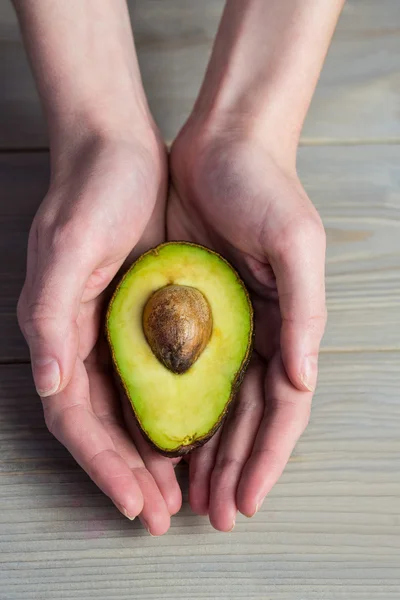 Женщина показывает свежий авокадо — стоковое фото