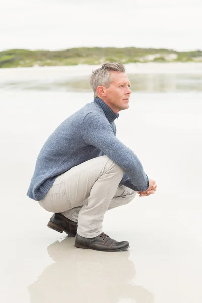 Man crouched down at the shore — Stock Photo, Image