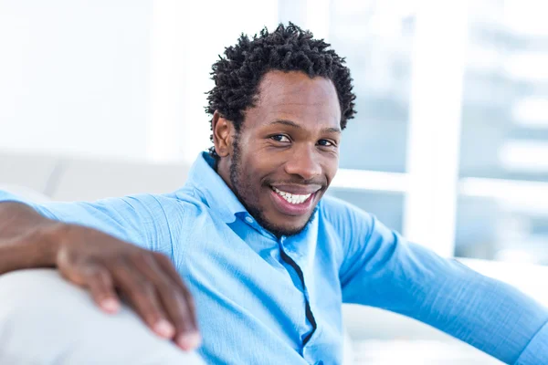 Homme souriant assis sur le canapé — Photo