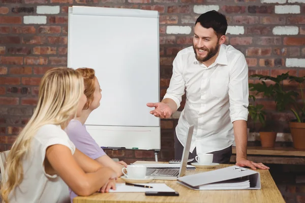 Empresario sonriendo mientras explica a sus colegas — Foto de Stock