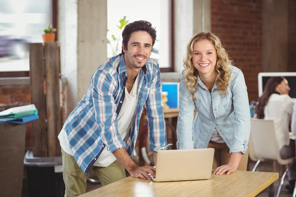 Colleagues smiling and standing by table — Stock Photo, Image