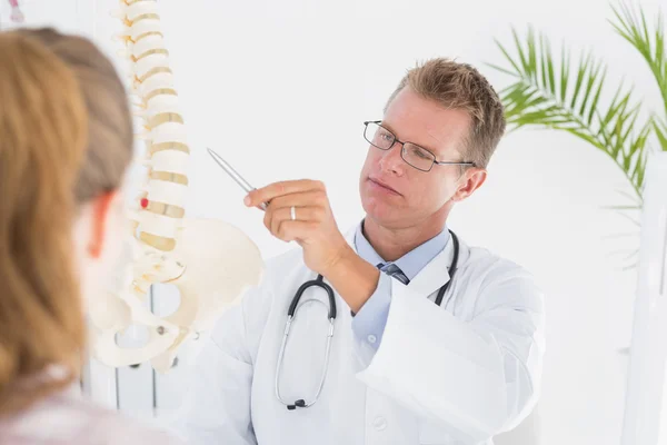 Doctor mostrando a su paciente un modelo de columna vertebral — Foto de Stock