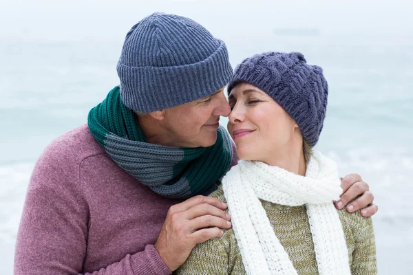 Paar mit Schals und Mützen am Strand — Stockfoto