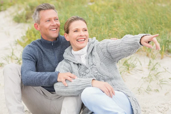 Smiling couple sitting on the sand — Stock Photo, Image