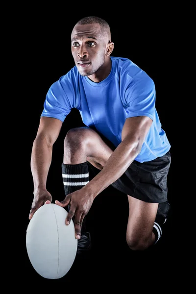 Rugby player holding ball while kneeling — Stock Photo, Image