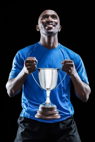 Atleta segurando troféu olhando para cima — Fotografia de Stock