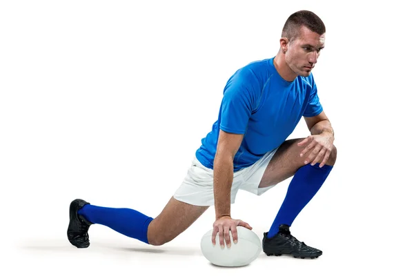 Rugby player stretching med boll — Stockfoto