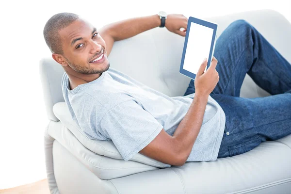 Man met tablet op sofa ontspannen thuis — Stockfoto