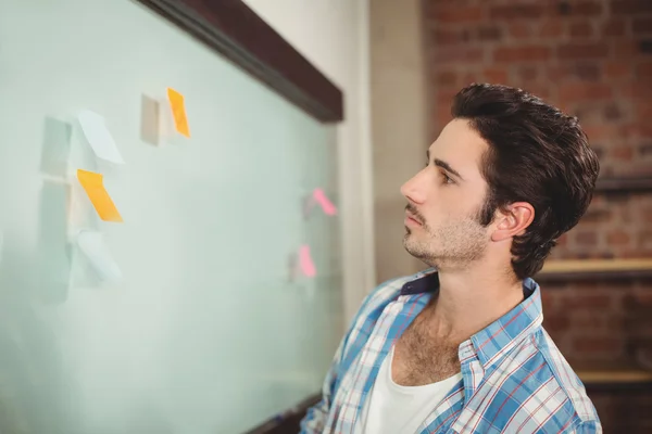 Businessman reading notes on glass board — Stock Photo, Image