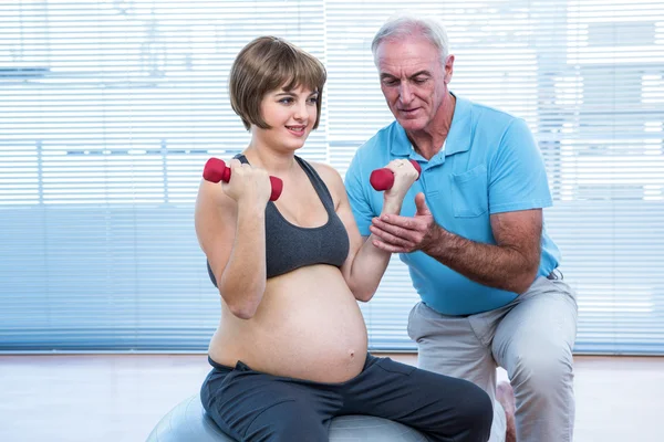 Інструктор навчає вагітної жінки займатися спортом — стокове фото