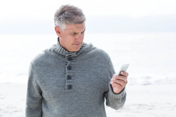 Mann steht mit Handy am Strand — Stockfoto